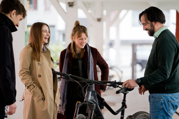 Eine Gruppe Menschen steht um ein Fahrrad herum und lachen gemeinsam.