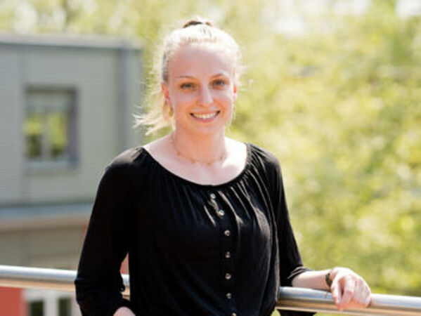 GLS-Nachhaltigkeitsbericht-2022-SophiaOrbach.jpg Sophia Orbach, die Leiterin des Projektes Nachhaltigkeitsbericht, blickt in die Kamera und lächelt. Im Hintergrund ist ein Teil des GLS Bank Gebäudes zu sehen und ein Baum.